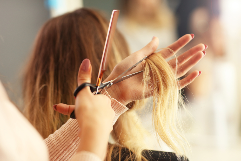 Hairdresser cutting long blonde hair