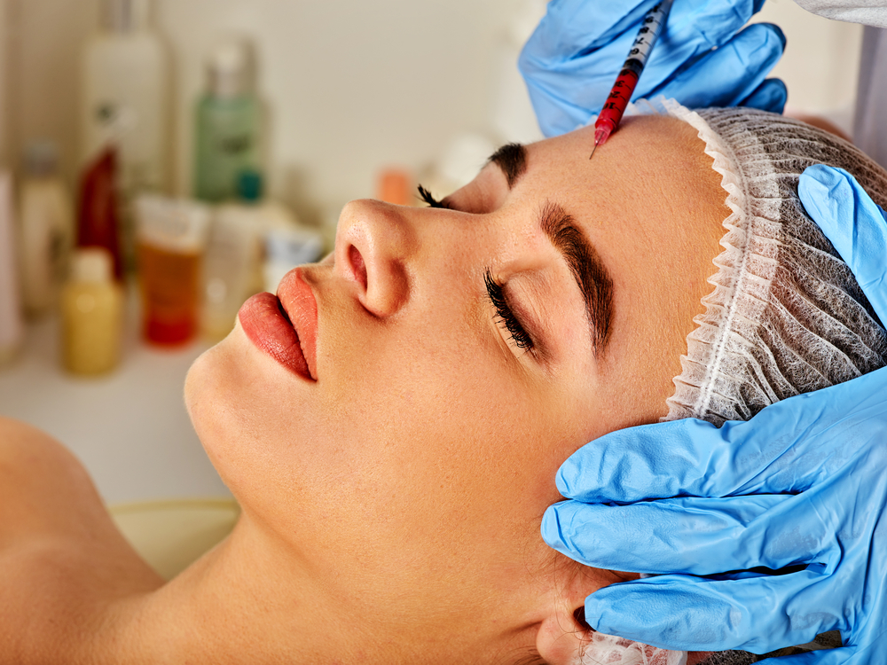 Woman having botox injections in her forehead